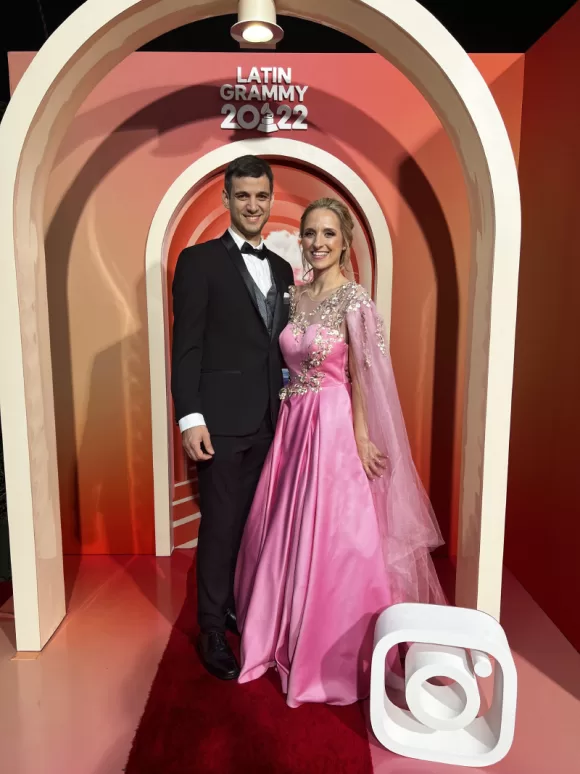 Athenas y Tobías Buteler, su esposo, posando con un fondo de los Latin Grammy 2022